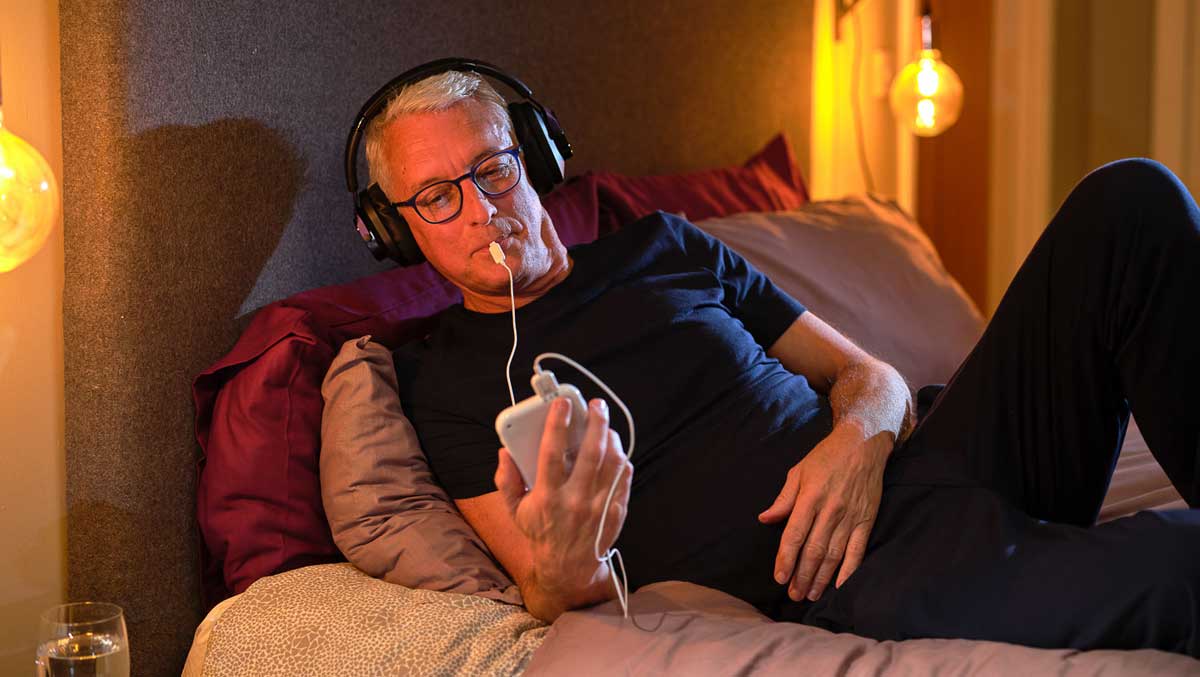 Man in bed using Lenire tinnitus treatment